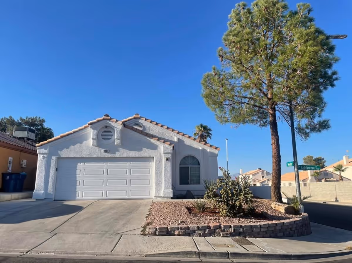 White stucco, single-story house with a two-car garage and desert landscaping.