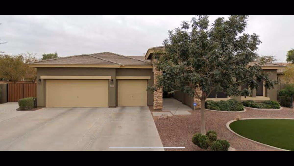A single-story beige building with a two-car garage and landscaped front yard.