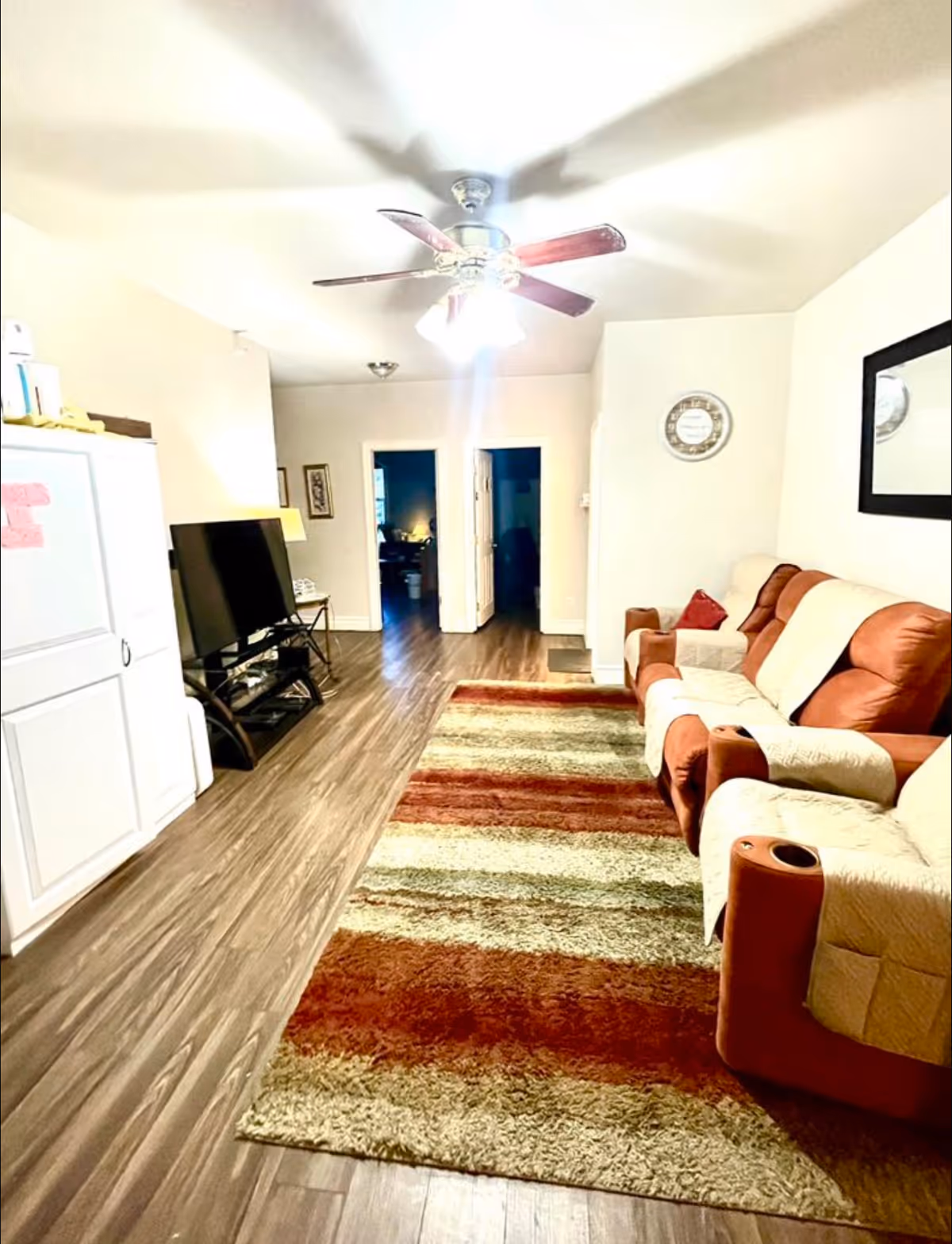 Cozy living room in a senior facility with brown-and-beige seating and ceiling fan.