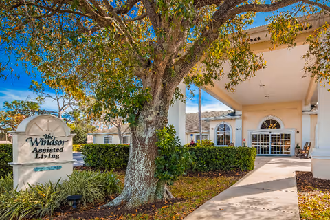 The Windsor Assisted Living sign beside a tree and entrance walkway.