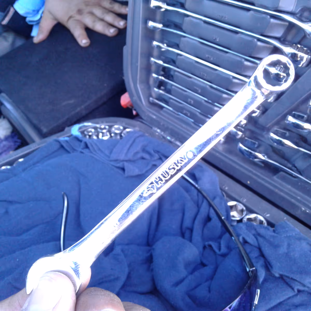Close-up of a shiny socket wrench inside a car trunk among clothing.