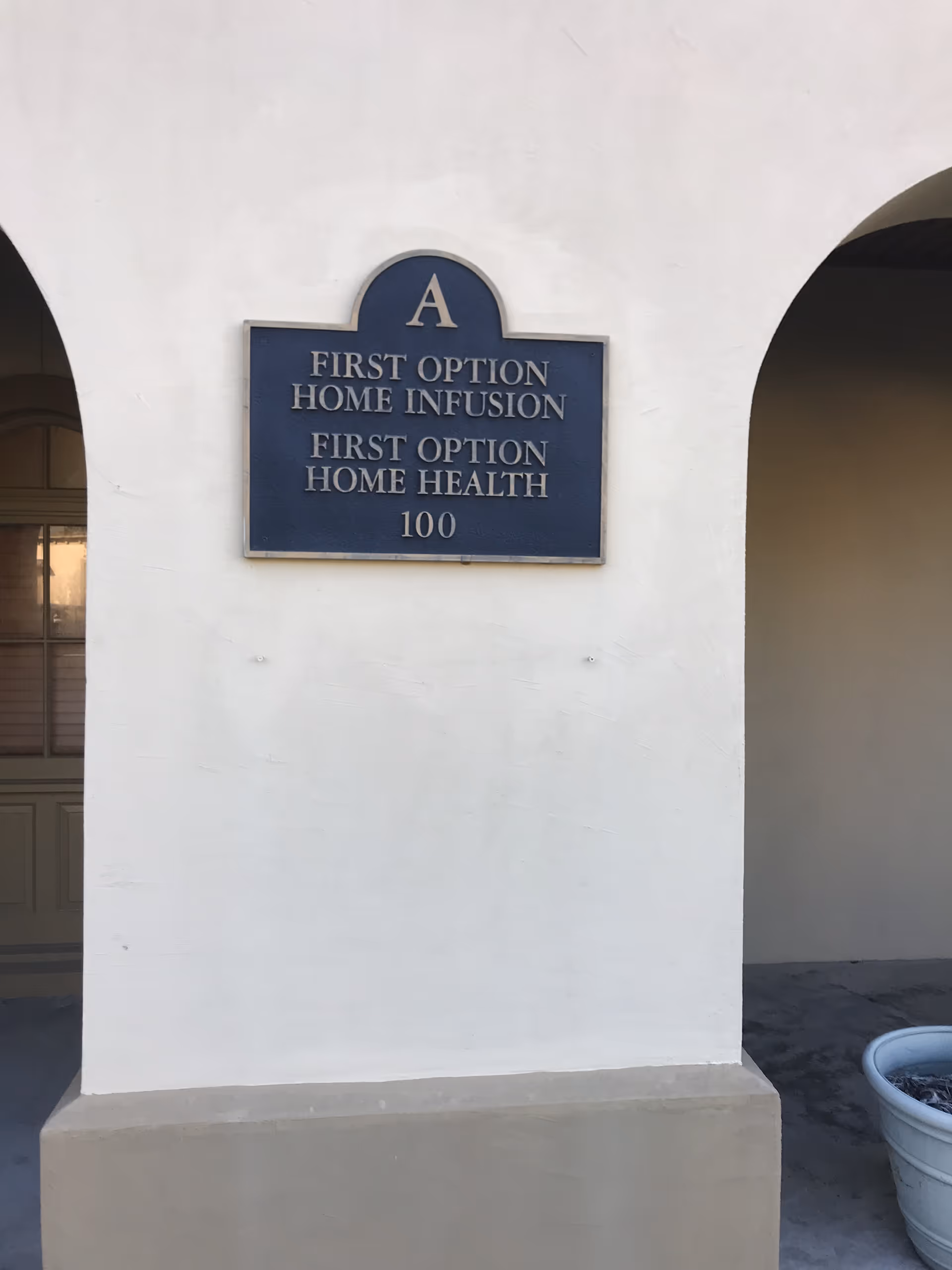 White exterior wall with a blue sign for First Option Home Infusion and Home Health.