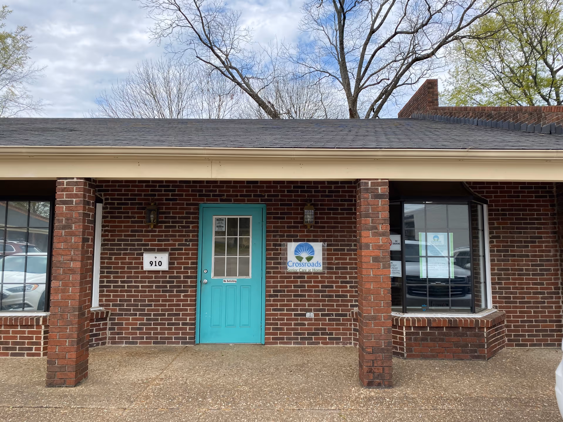 Brick building exterior with turquoise front door and Crossroads Senior Care at Home sign.