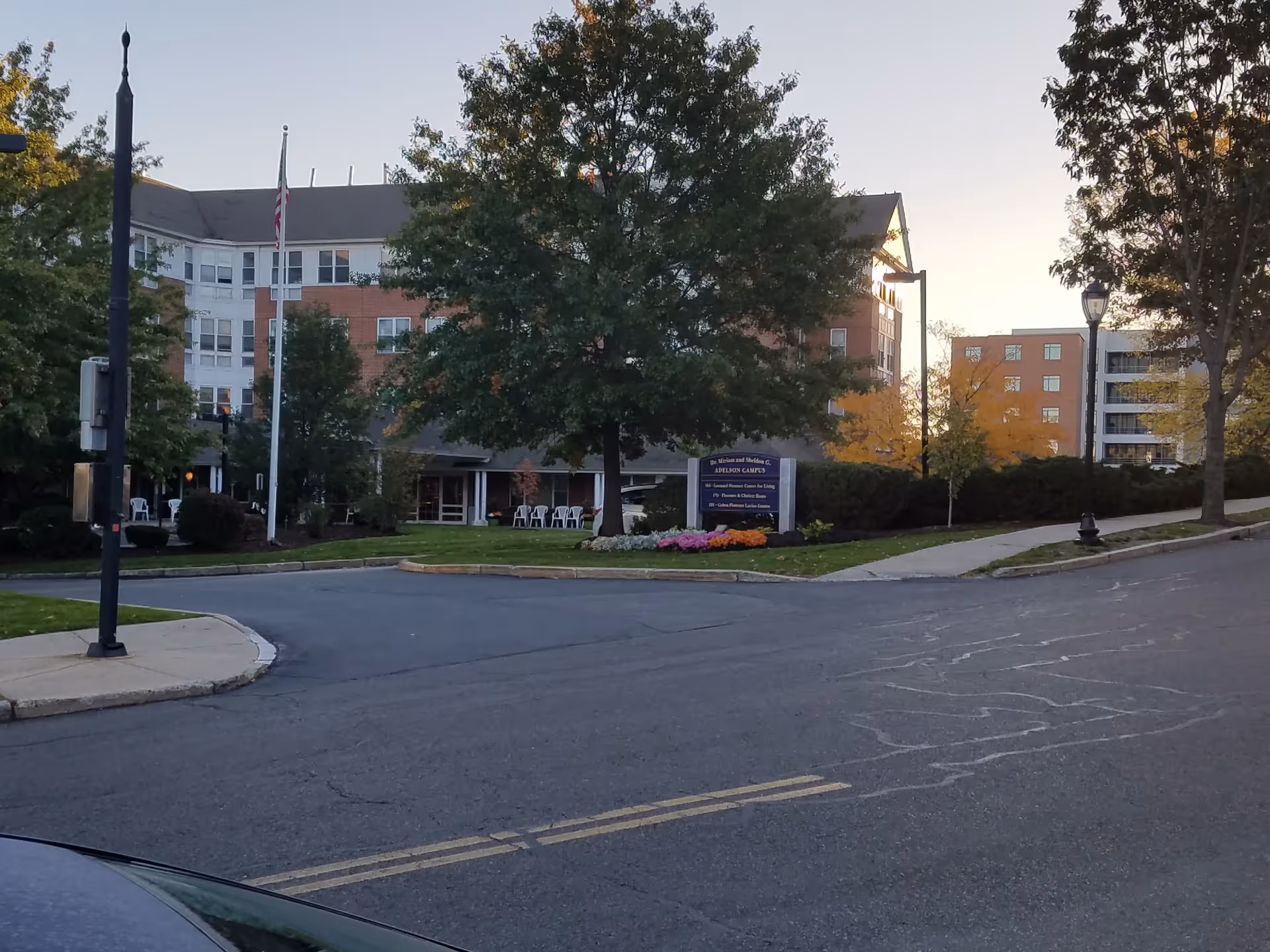 Exterior view of Leonard Florence Center for Living with trees, entrance, and outdoor seating.