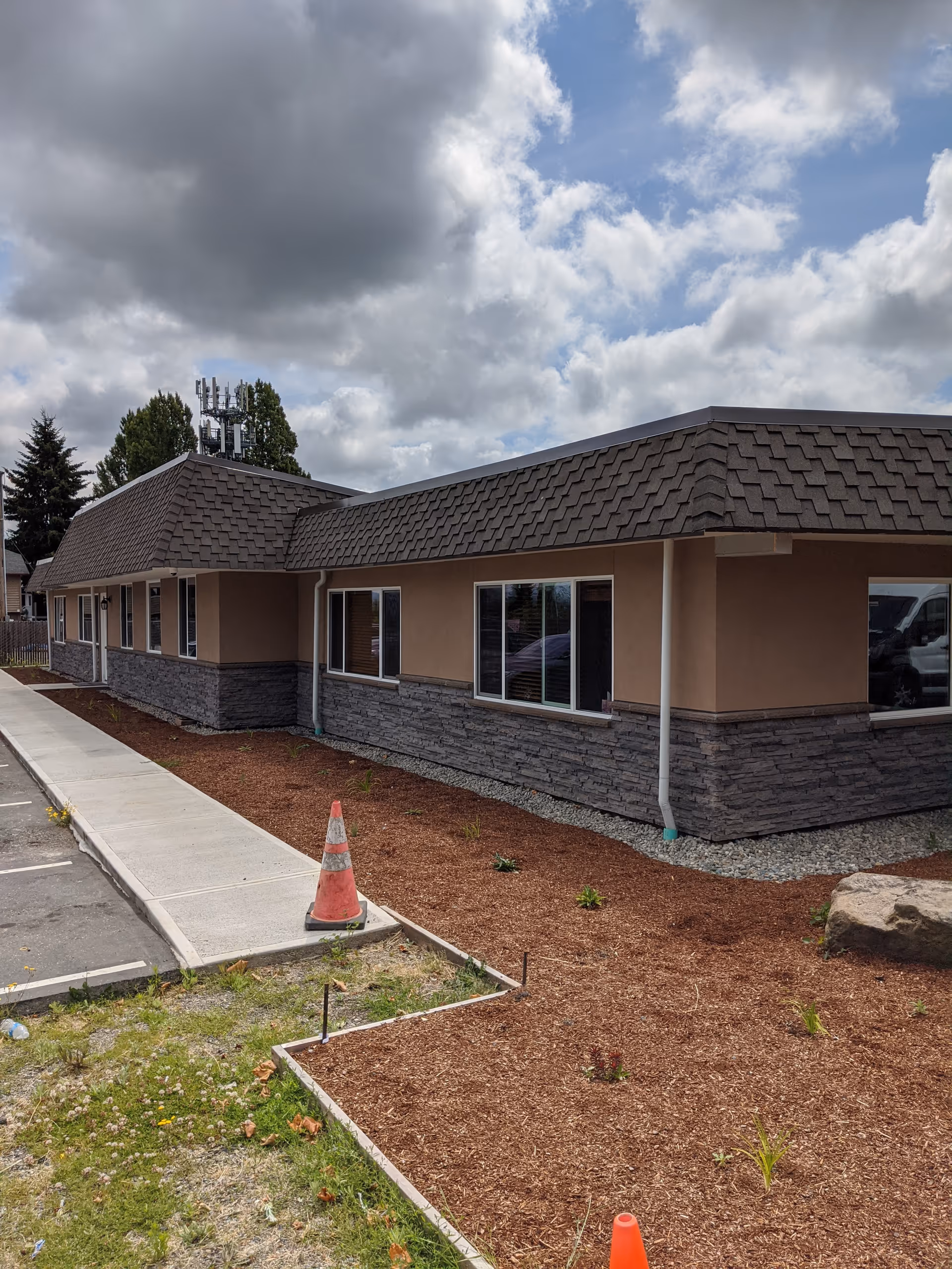 Single-story senior living facility exterior with beige walls, stone base, and a sidewalk.
