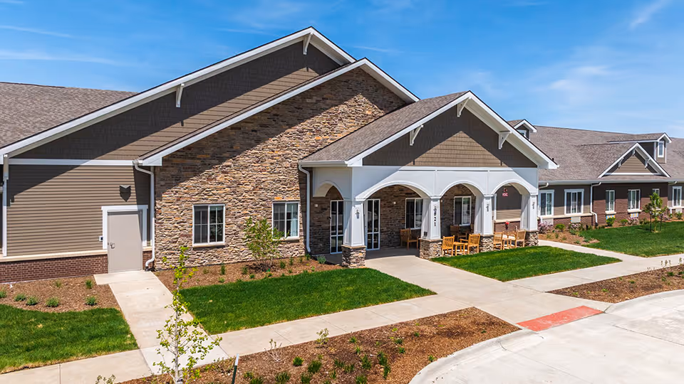 Exterior view of Edencrest at Adel showing stone facade and front porch seating.