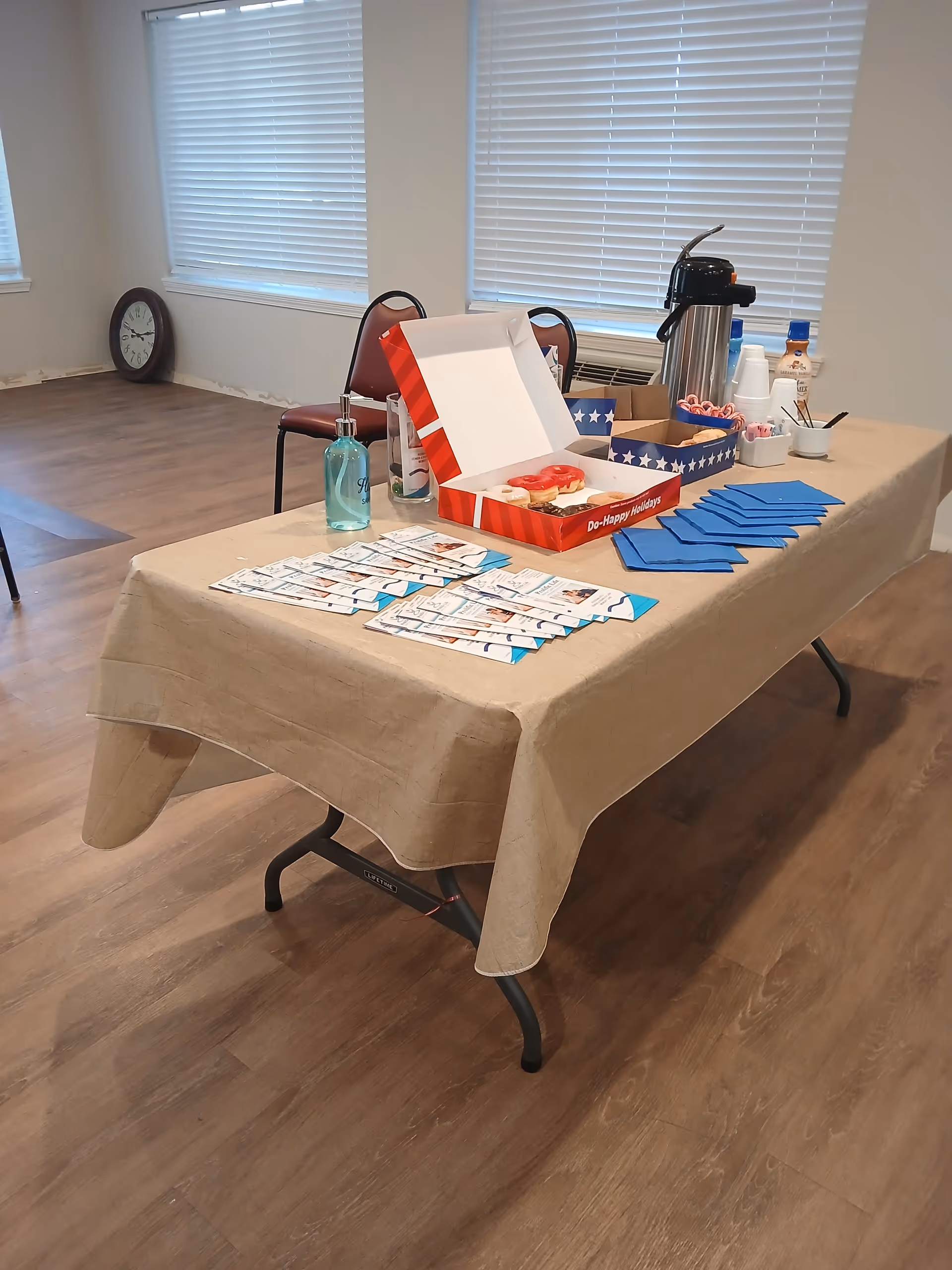 Refreshment table setup with donuts and beverages in a Prolific Life Home Care Solutions LLC facility.