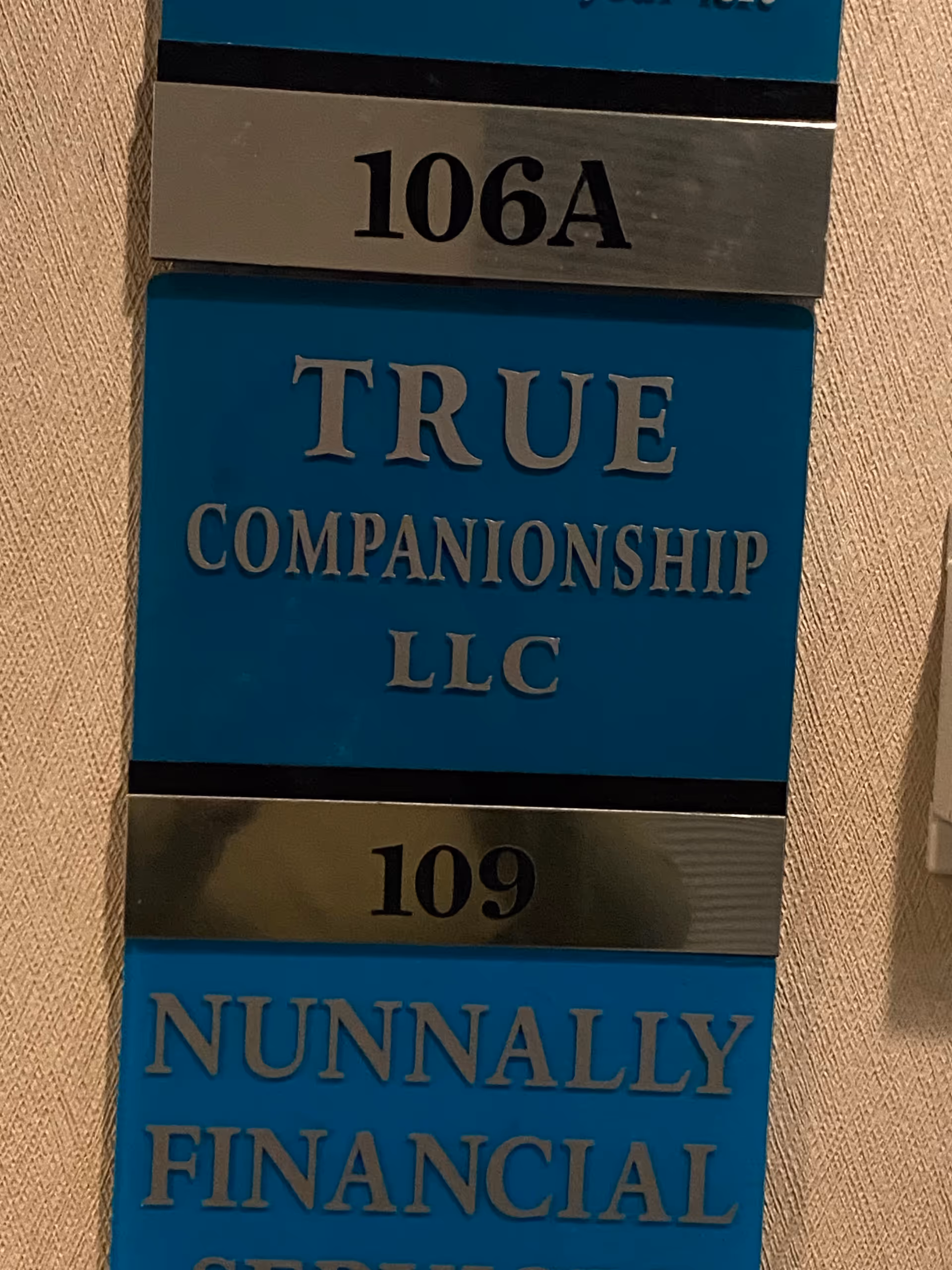 Blue wall plaque displaying True Companionship LLC and suite numbers 106A and 109.