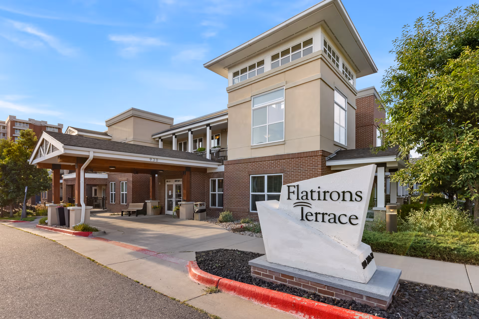 Exterior view of Flatirons Terrace Senior Living entrance with a large stone sign.