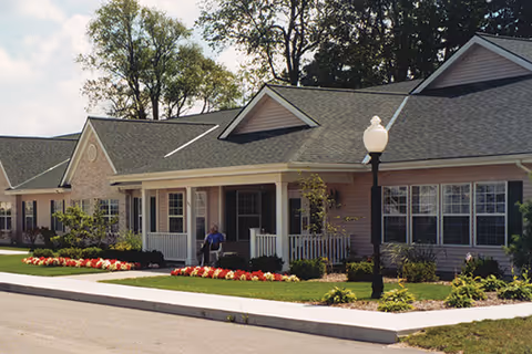 Exterior view of Green Acres of Greenville showing front porch, landscaping, and a lamp post.
