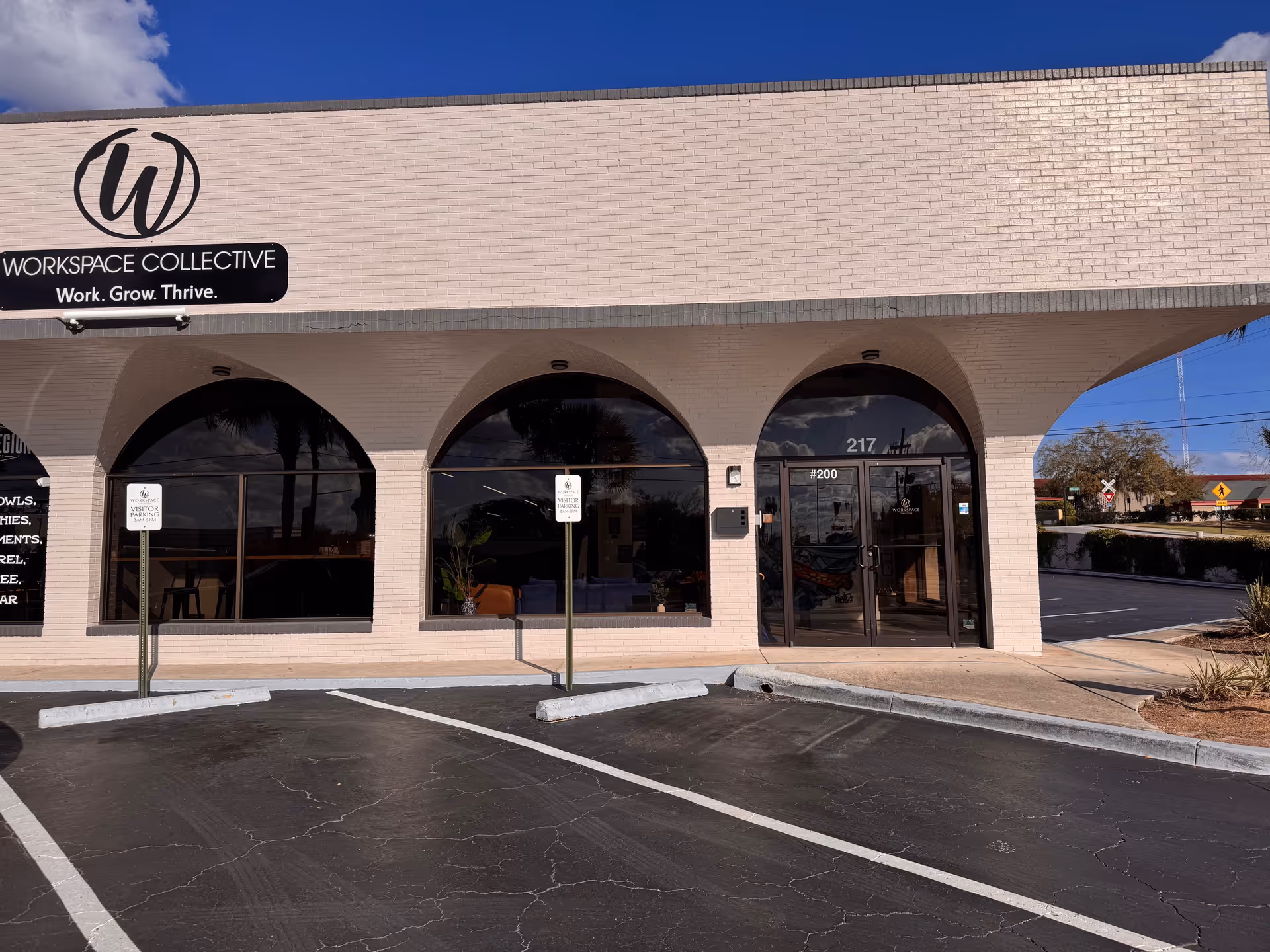 Beige brick storefront with arched windows and a Workspace Collective sign.