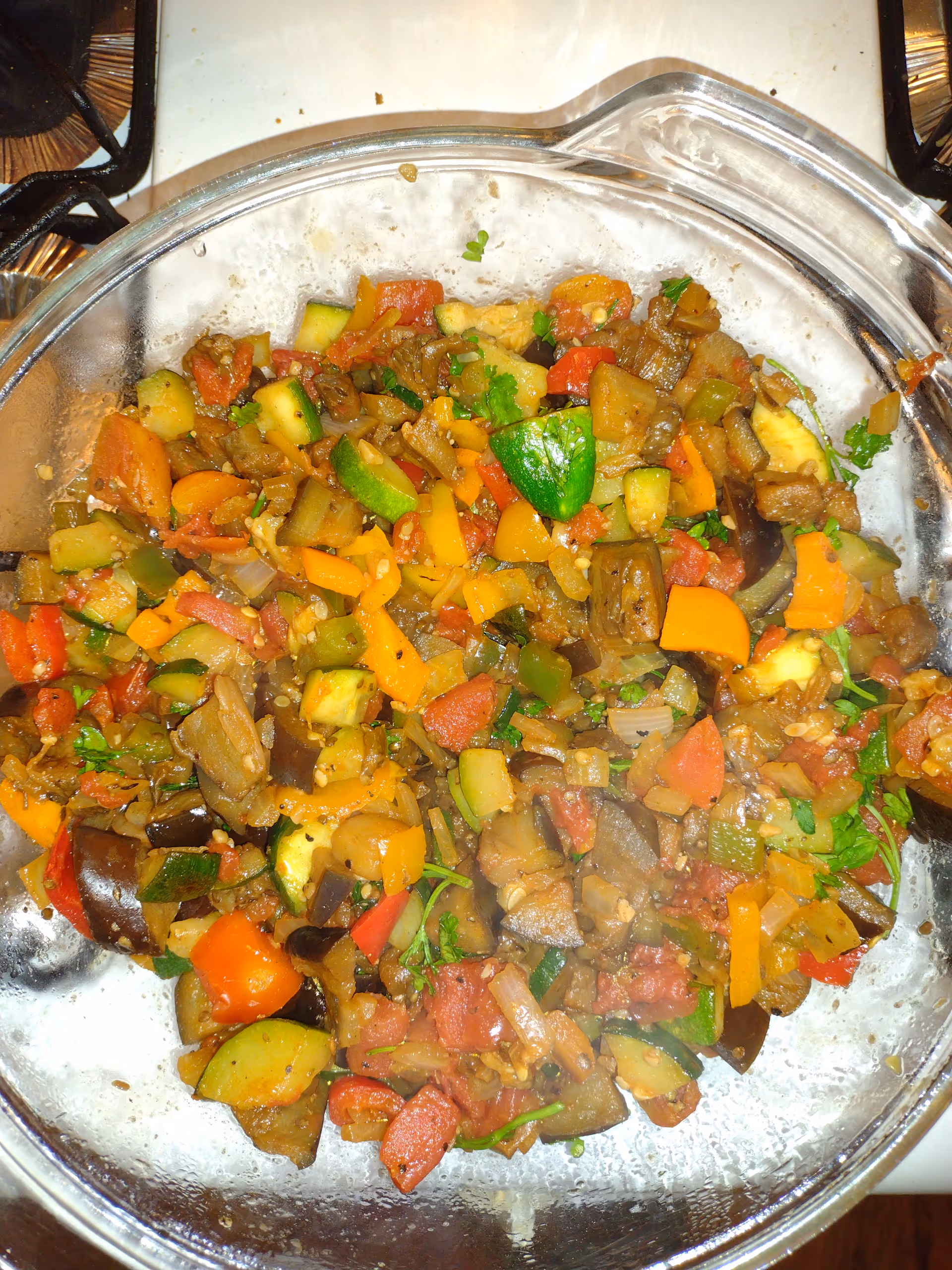 A stainless steel pot filled with colorful chopped vegetables simmering on a stovetop.