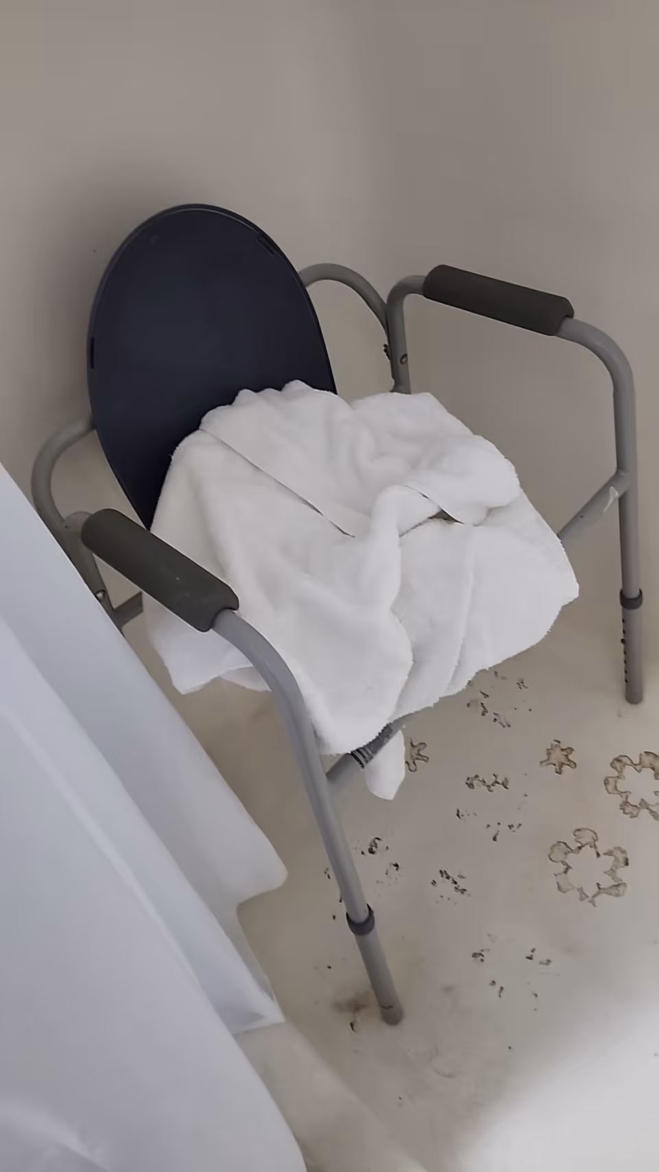 Metal-framed chair with padded arms and a white blanket in a plain interior.
