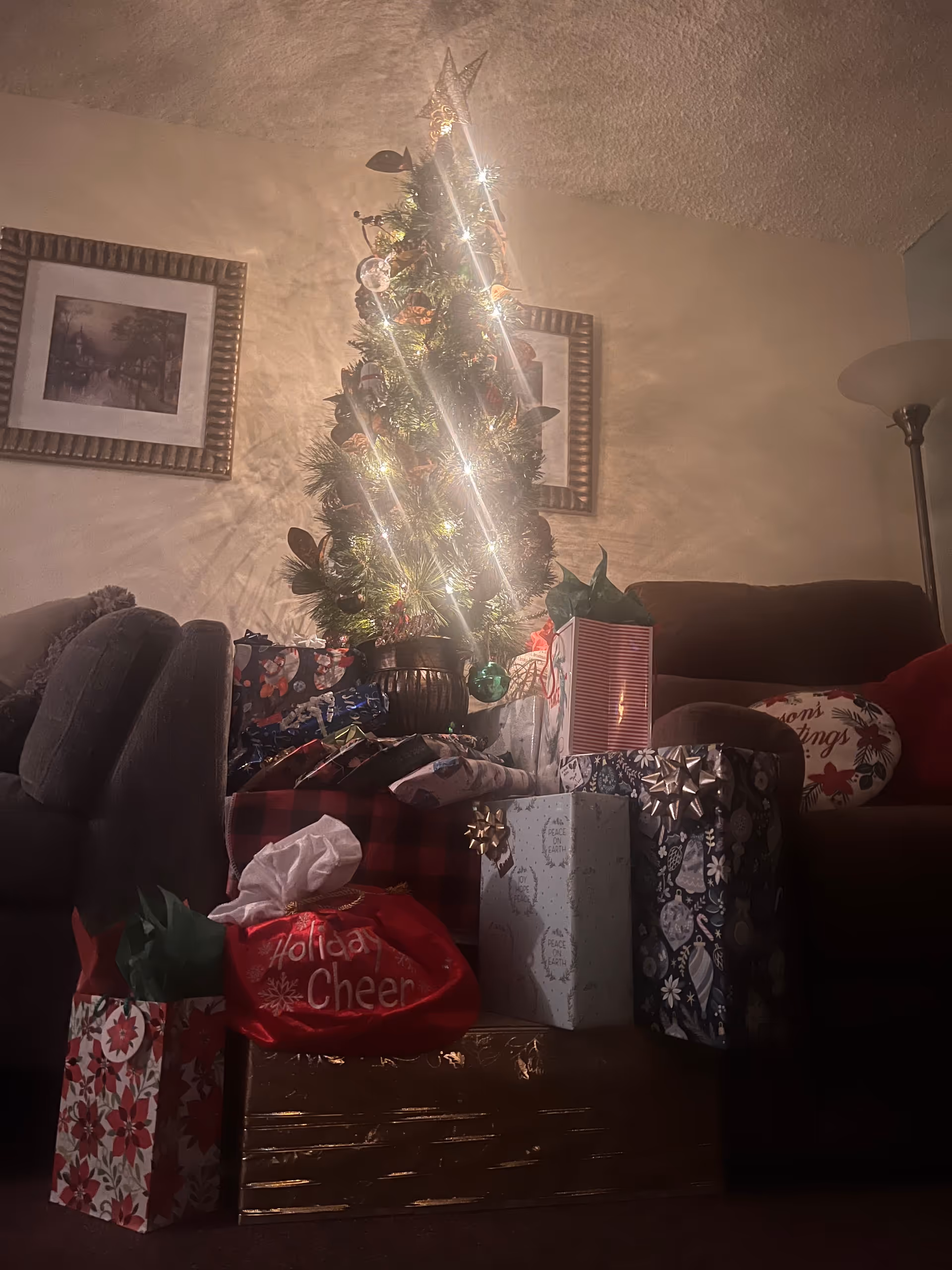 Warm living room scene with a decorated Christmas tree, wrapped gifts, and a sofa.
