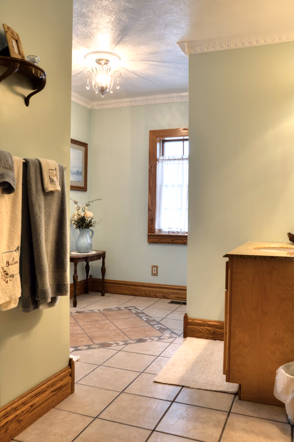 Interior bathroom area with towels on a rack, a vanity, window, and tiled floor.