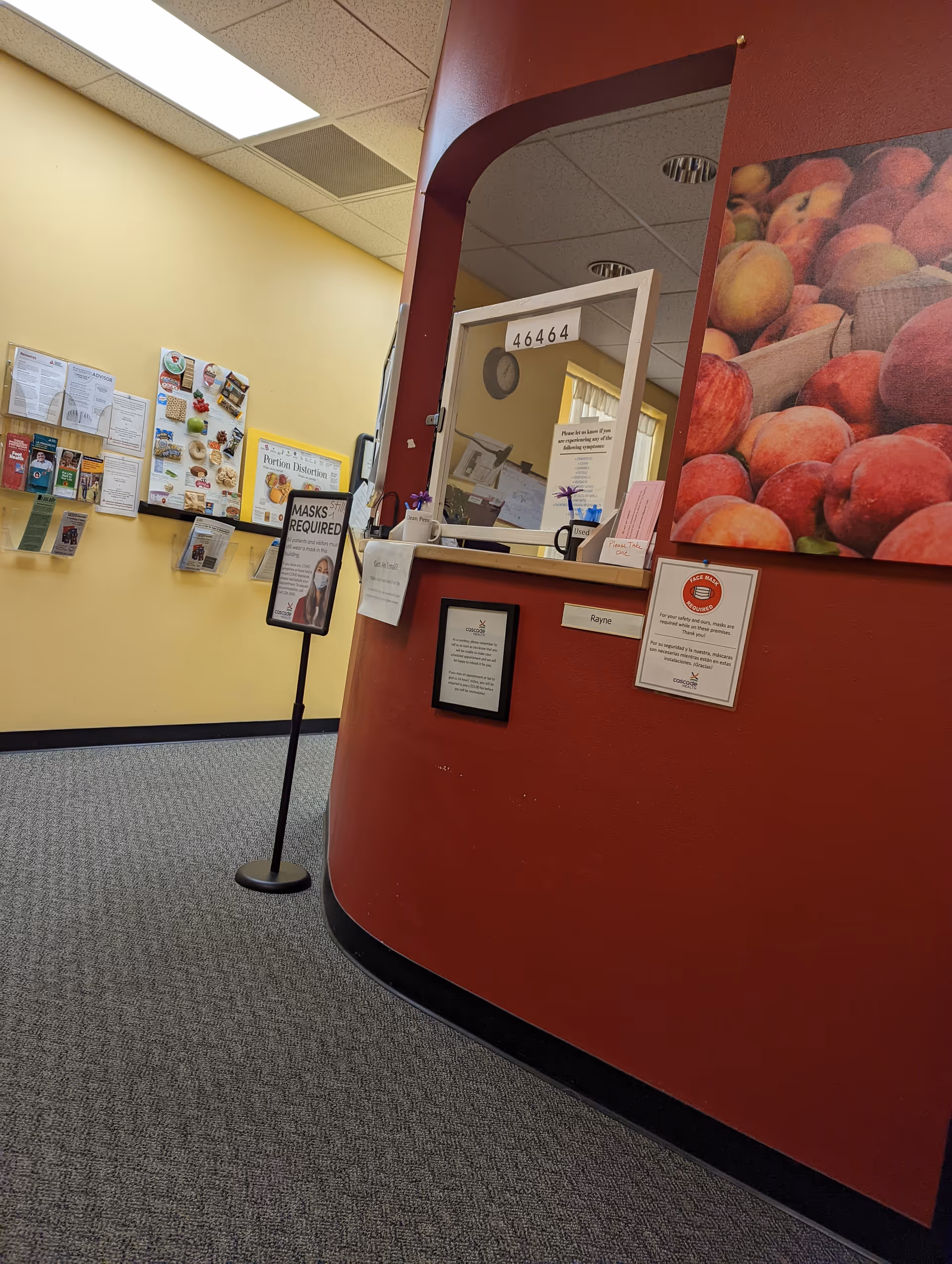 Red curved wall with reception window and bulletin boards in a lobby.