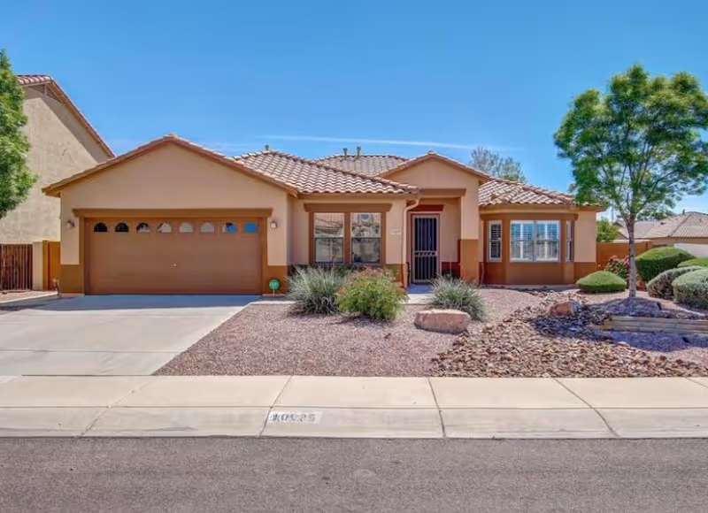 A single-story desert-style house with a two-car garage and xeriscaped front yard.