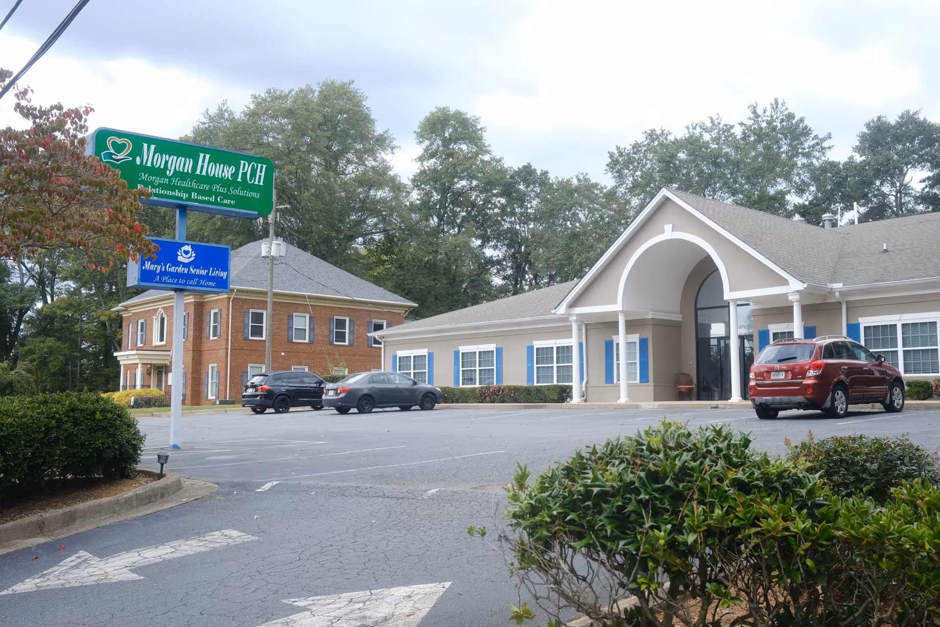 Exterior view of Mary's Garden Senior Living facility with signs and parked cars.