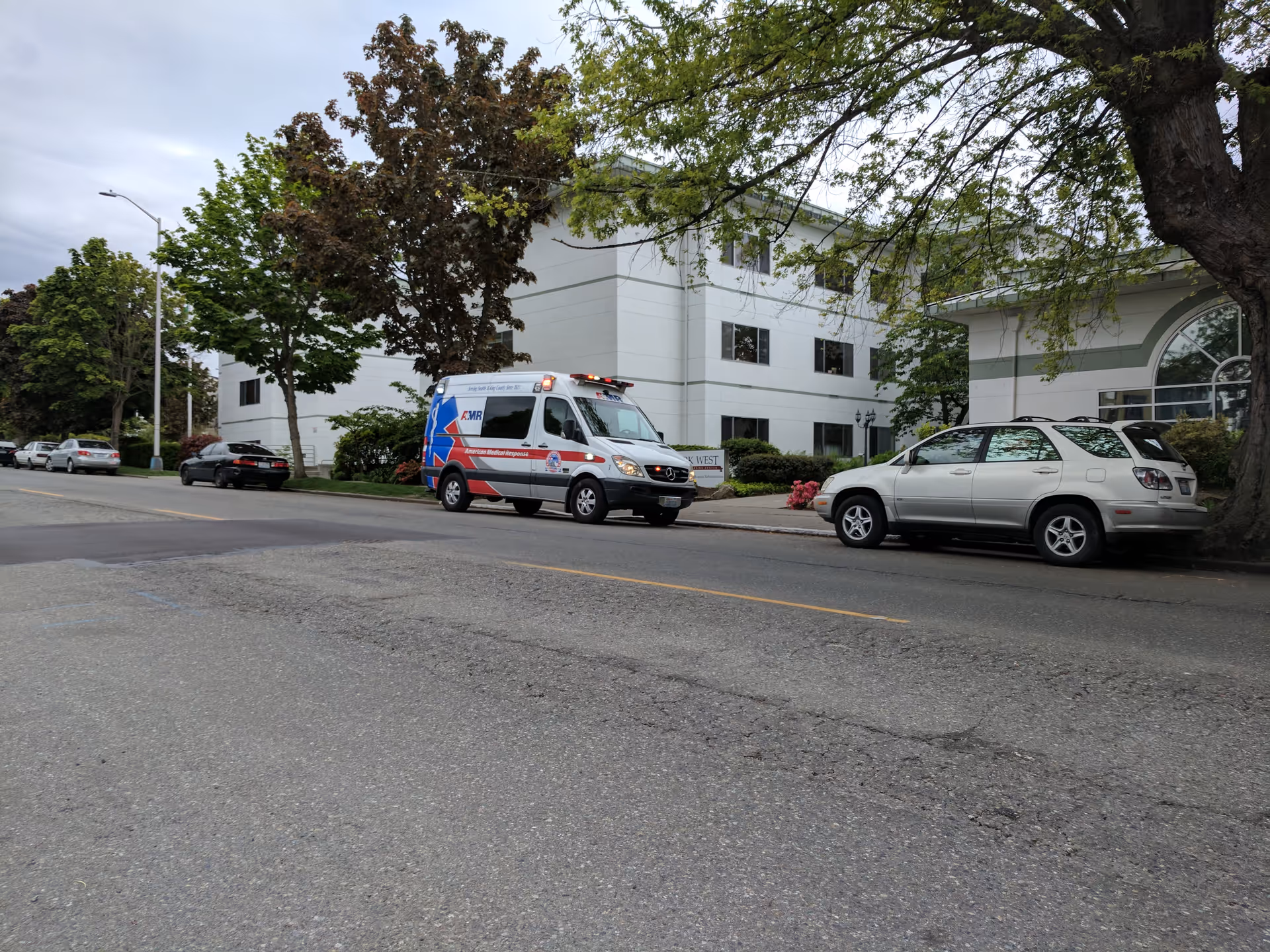 Ambulance and cars parked along a street in front of Avamere Rehabilitation at Park West.