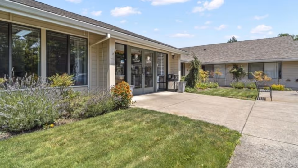 Exterior view of a senior care facility entrance with glass doors and landscaping