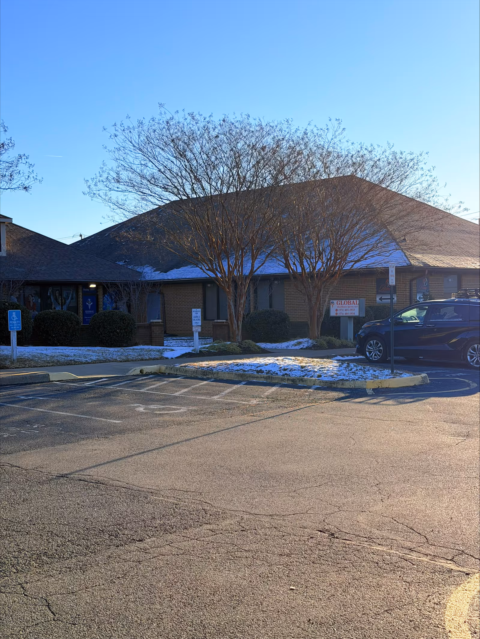 Single-story brick senior care facility exterior with trees, parking, and Global sign.