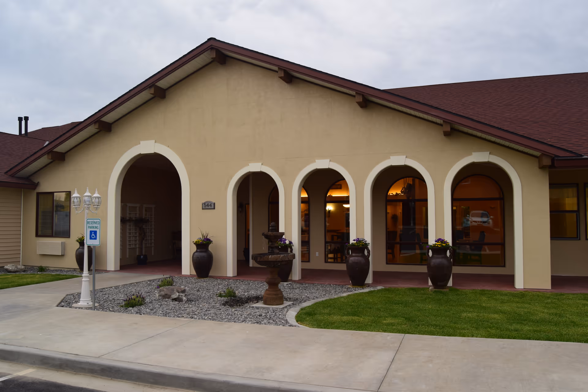 Beige senior facility with arched entrances and planters along a landscaped front.