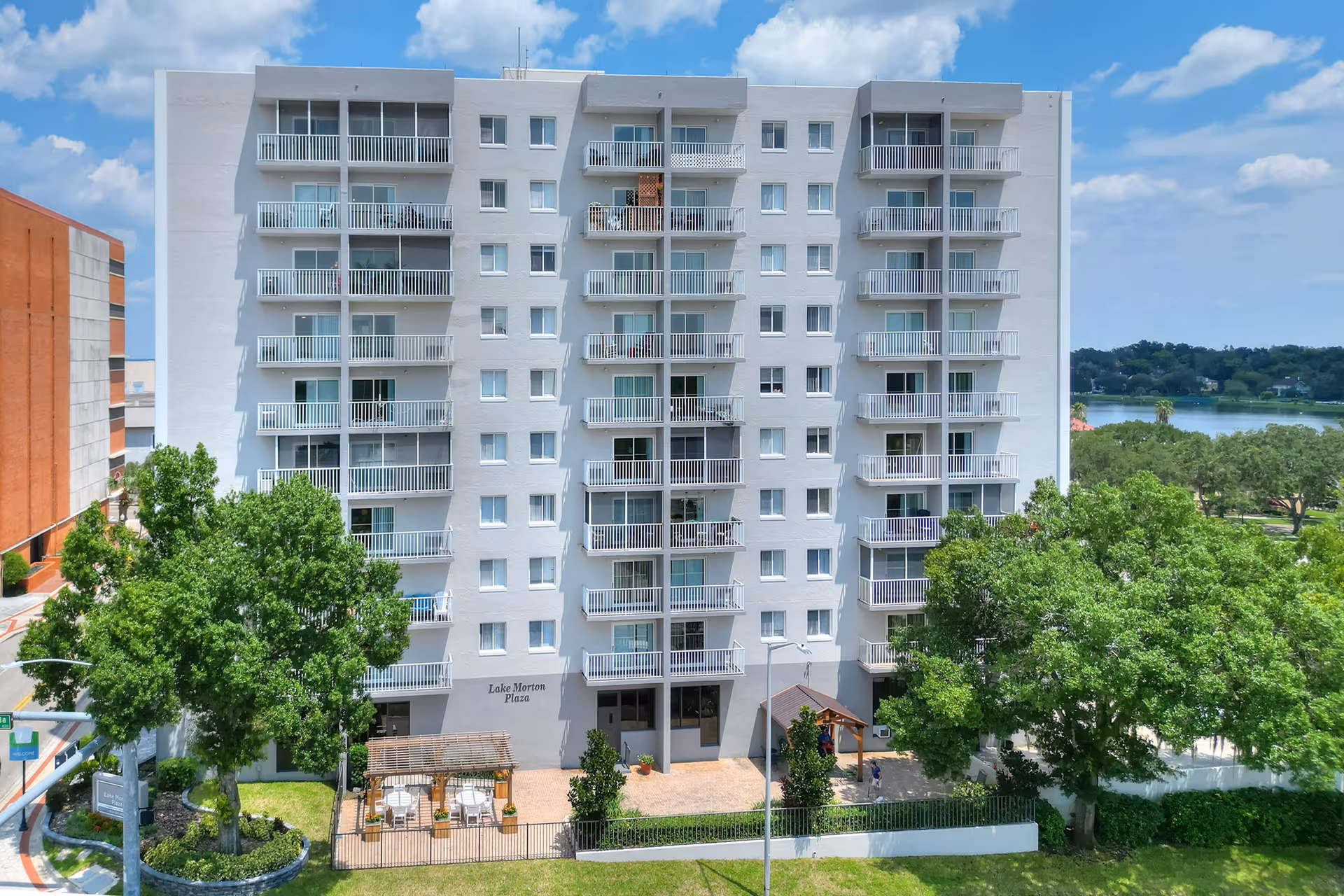 Exterior view of Lake Morton Plaza, a white multi-story senior living building with balconies.