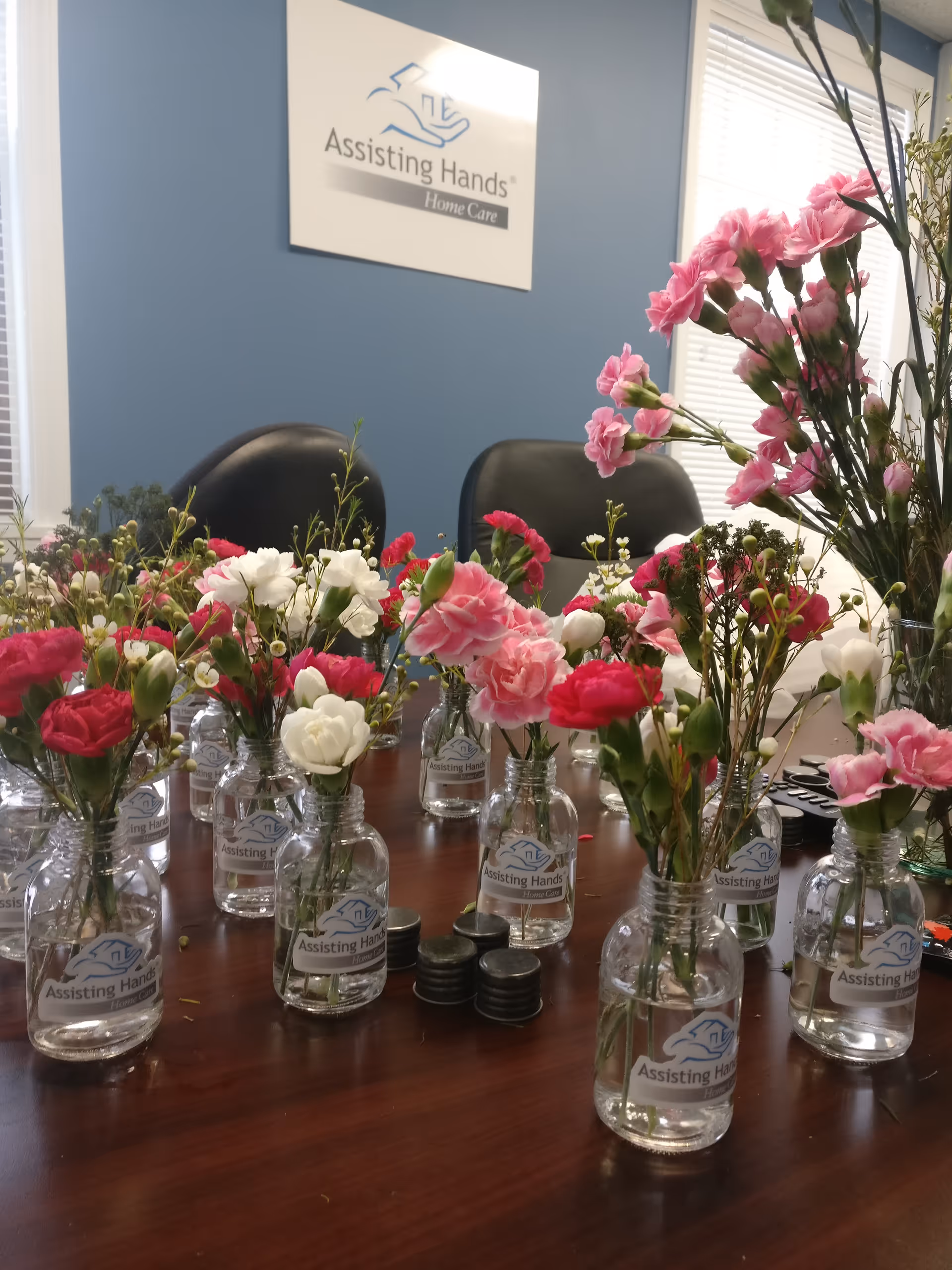 Interior meeting room with Assisting Hands sign and glass jar flower centerpieces.