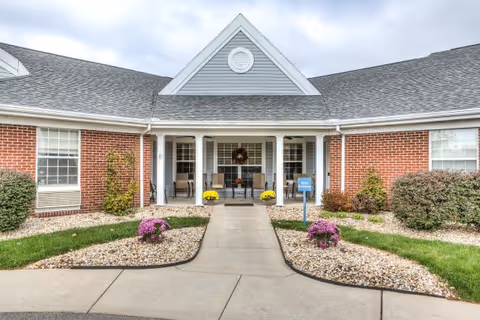 Front view of a brick senior living facility entrance with a landscaped walkway.