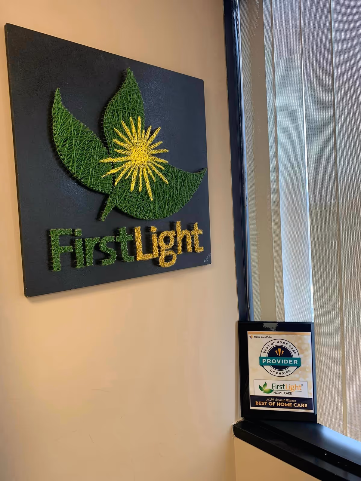 Indoor wall sign with FirstLight logo and window blinds in a hallway.