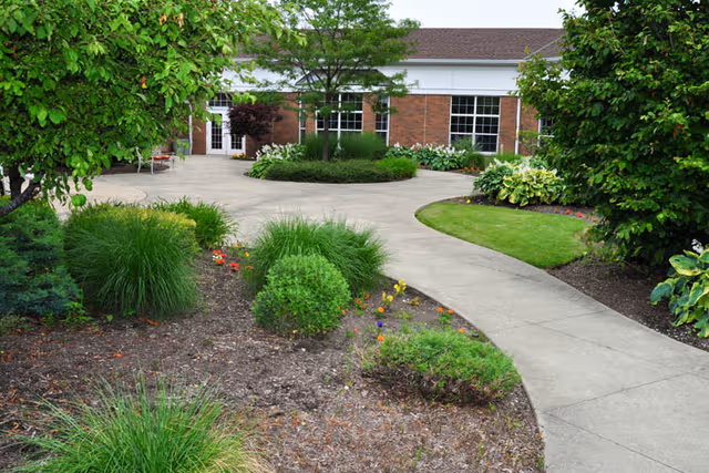 Curved walkway winds through landscaped garden toward Governor's Village by StoryPoint entrance.