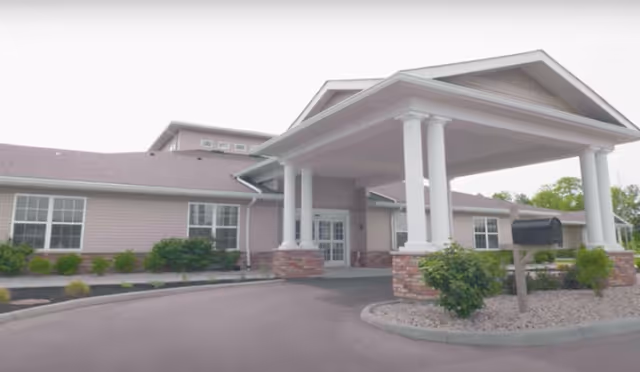 A single-story senior living facility exterior with a covered entrance and driveway.