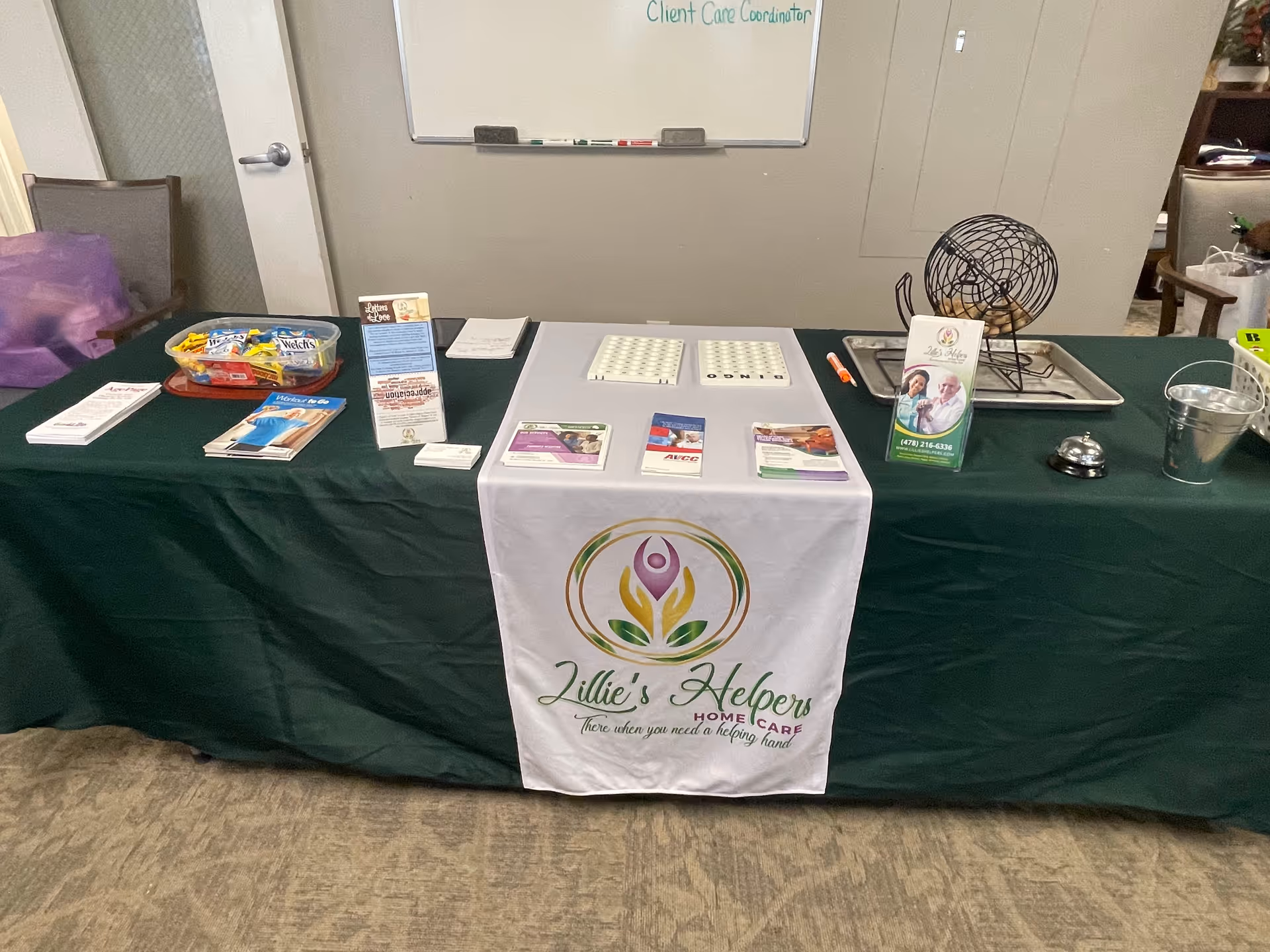 A promotional information table with brochures and a banner for Lillie's Helpers Home Care.