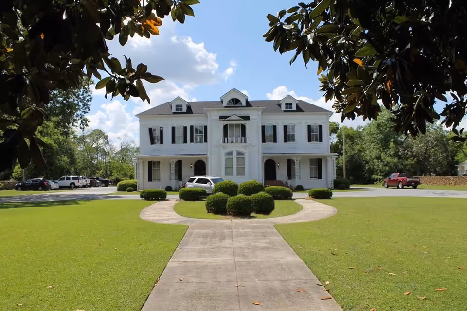 White, two-story facility building with a circular driveway and manicured lawn.
