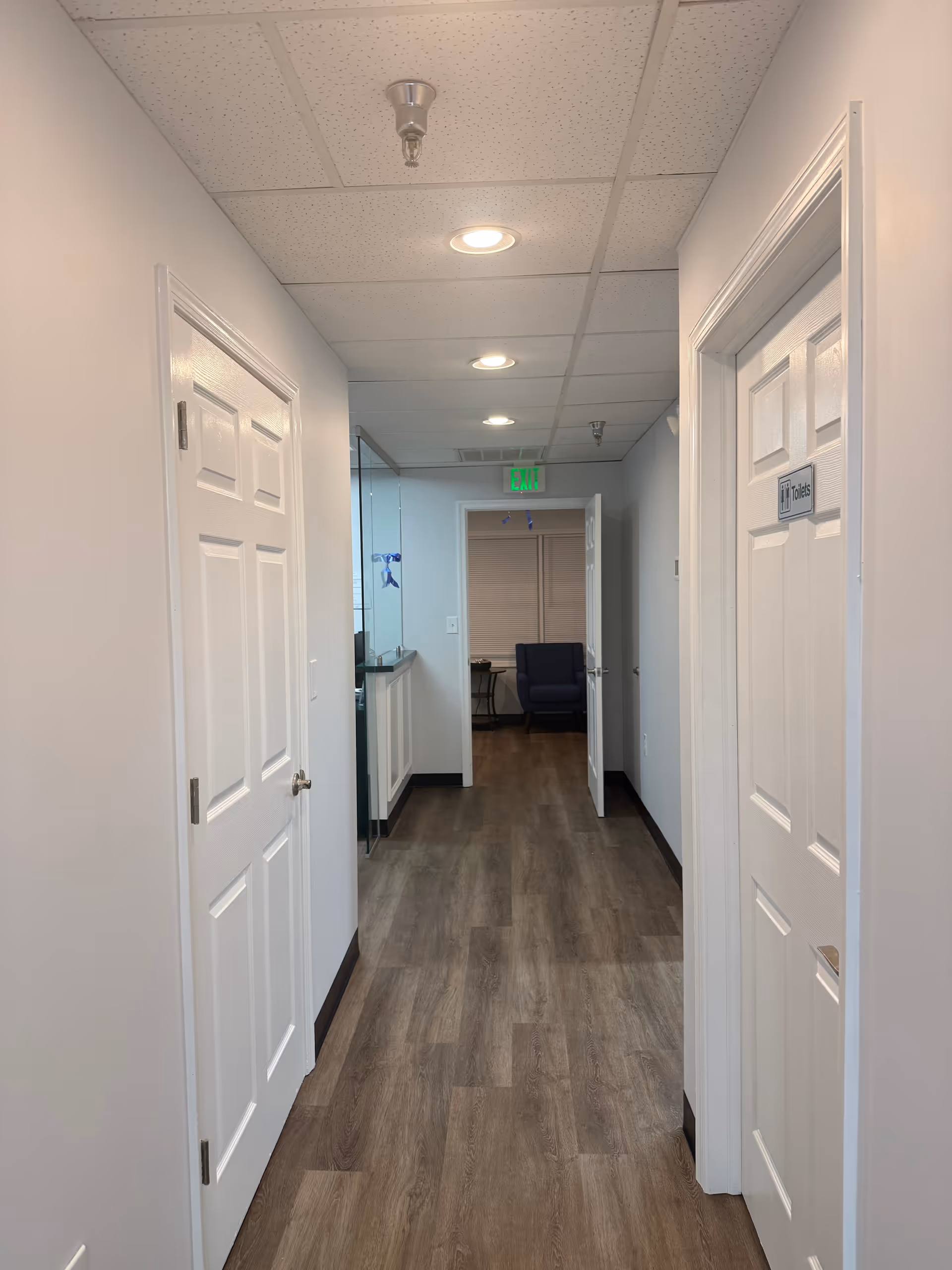 Long interior hallway with doors on both sides and a distant seating area.
