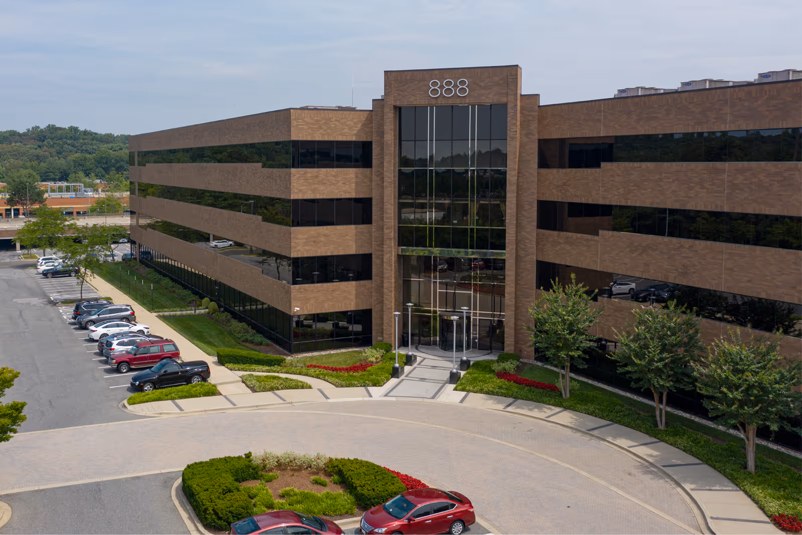 Aerial view of a brick building with a glass front and surrounding parking.
