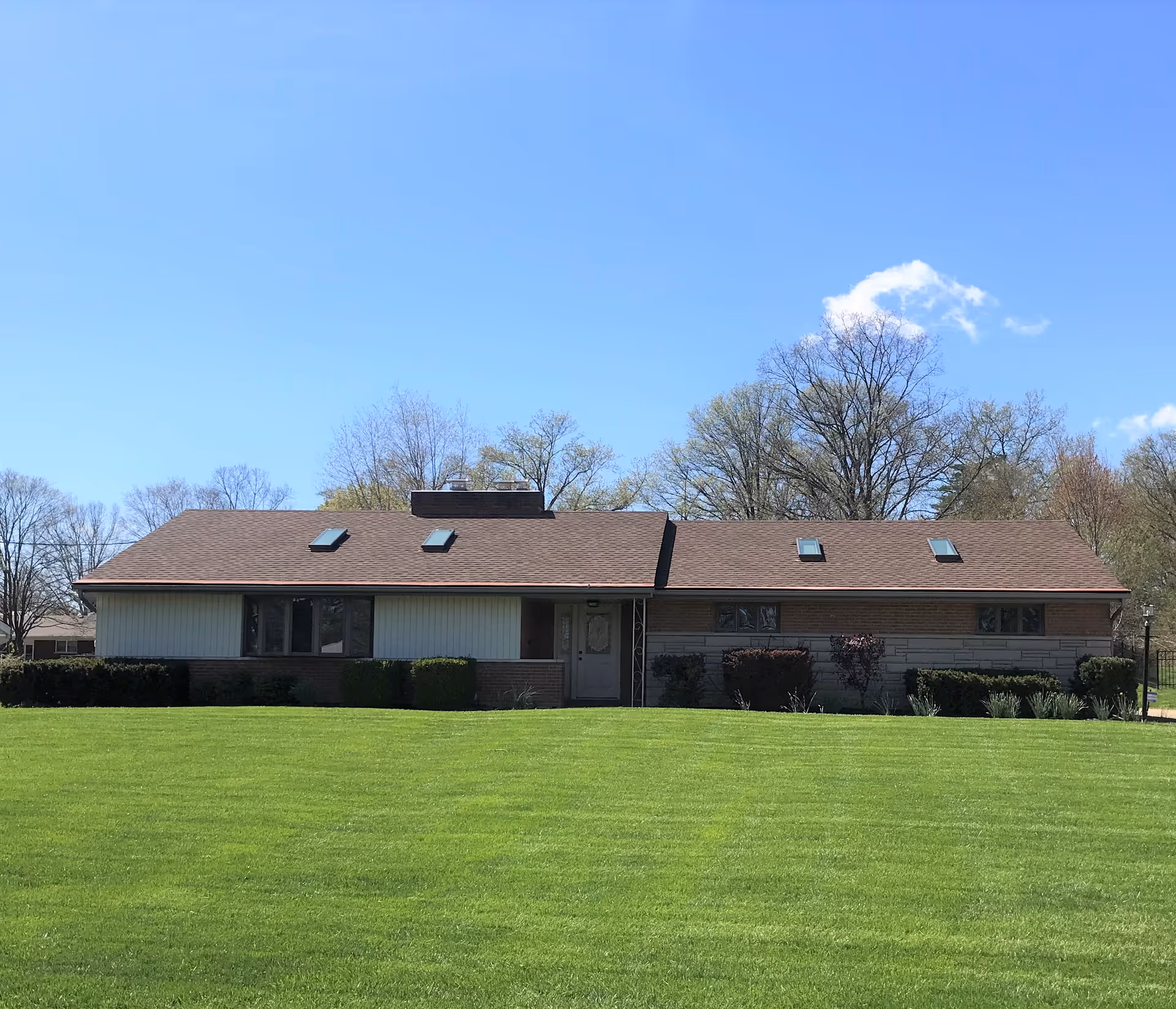 Single-story facility building with brown roof and expansive green lawn.