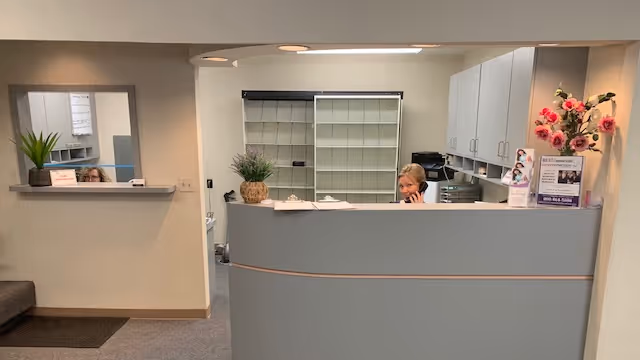 Reception area of a senior care facility with a curved front desk and staff.
