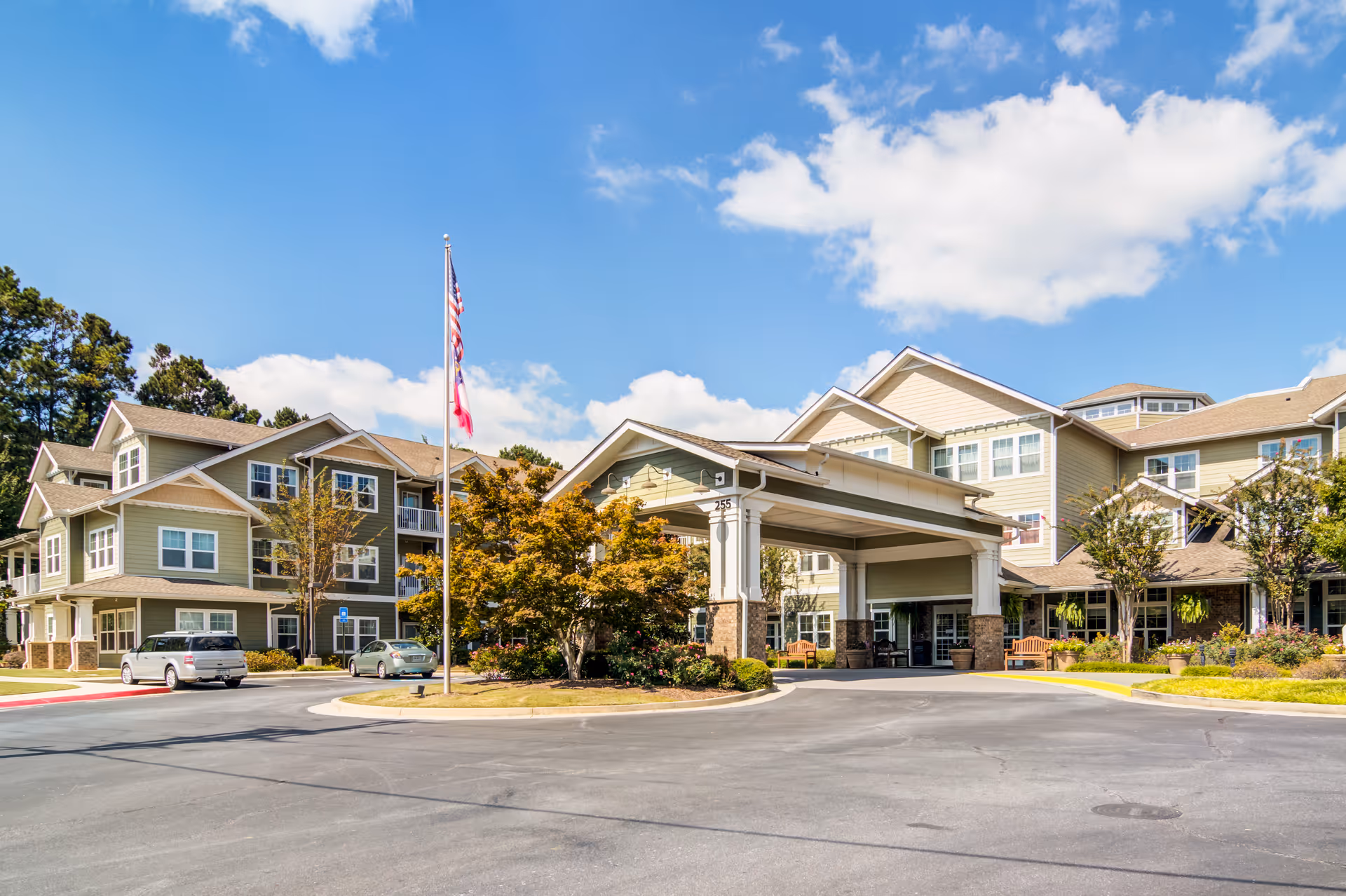 Exterior view of Cottonwood Estates Gracious Retirement Living entrance with parked cars.
