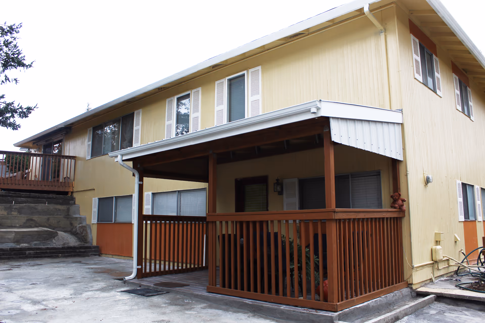 Exterior view of a two-story yellow senior living facility with brown porch.