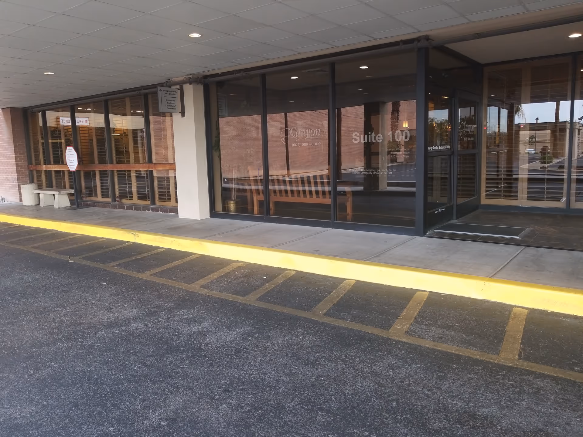 Exterior view of Canyon Surgery Center front with glass doors and a yellow curb.