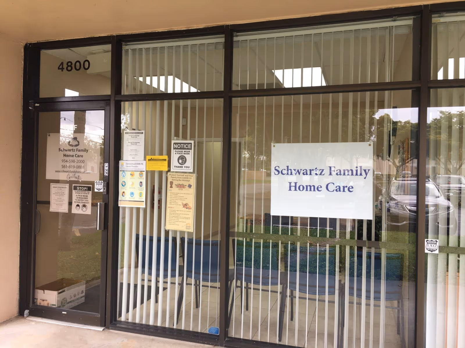 Glass front entrance of Schwartz Family Home Care with blinds and signs.