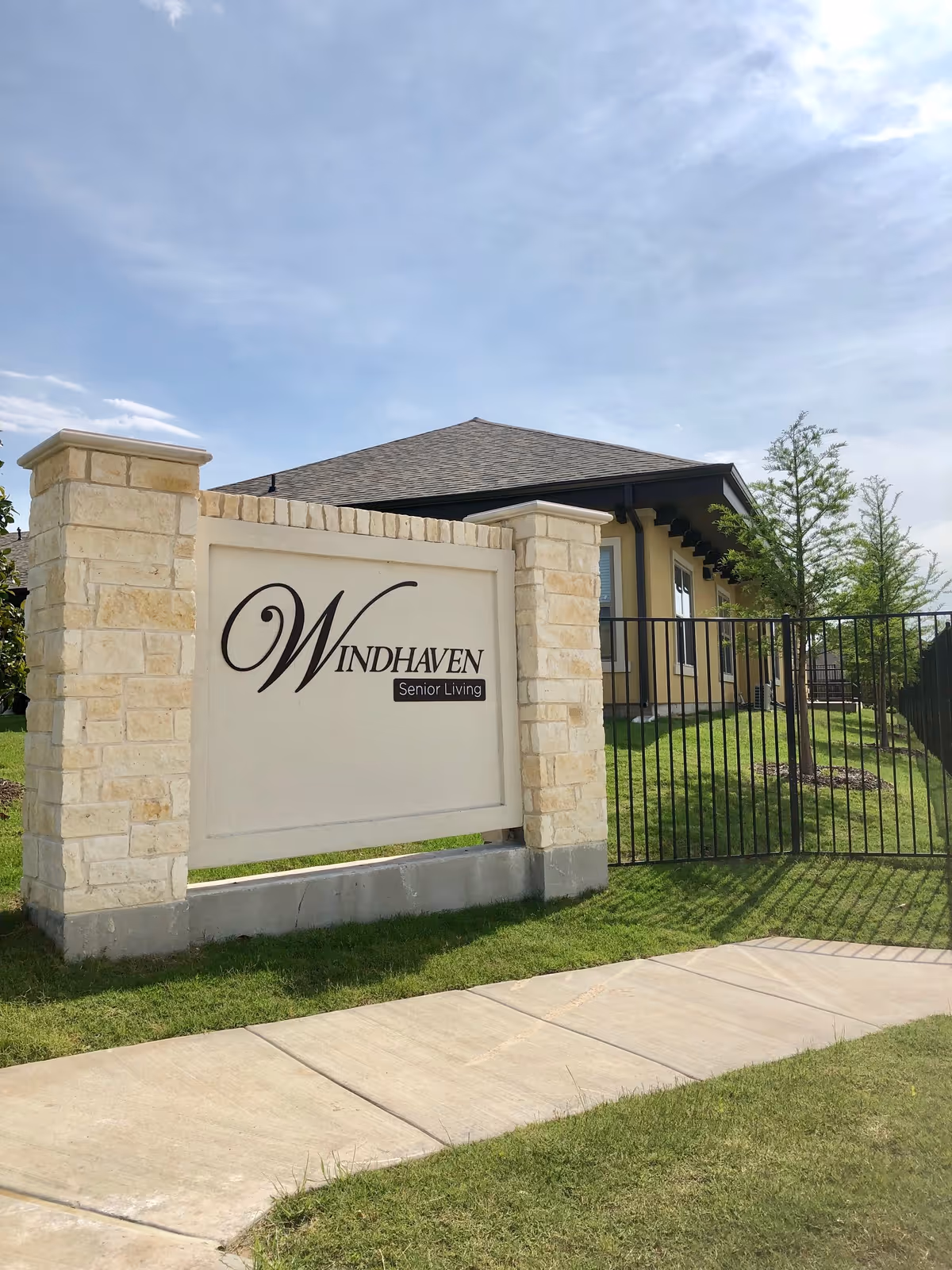 Stone entrance sign reading Windhaven Senior Living beside a gated building exterior.
