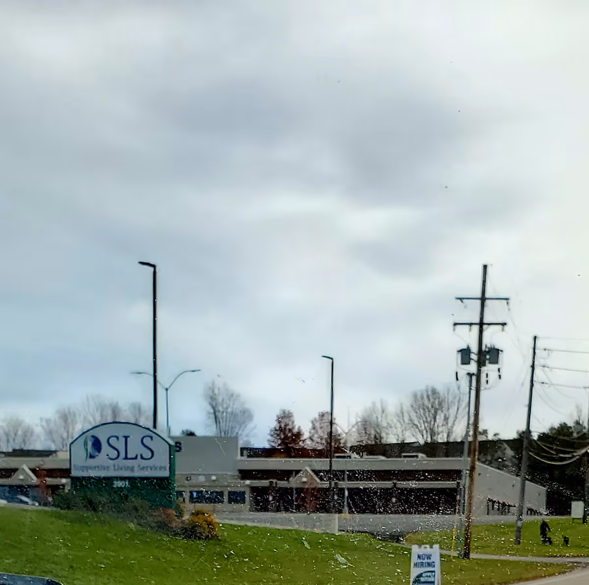 Exterior view of a senior living facility with SLS sign and green lawn.