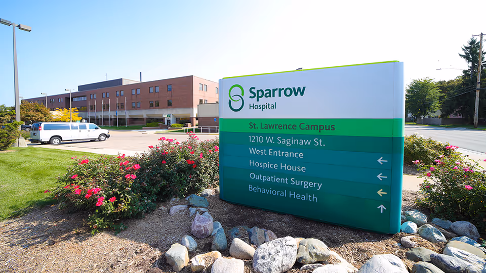 Outdoor Sparrow Hospital sign with campus directions beside a brick building and flowers