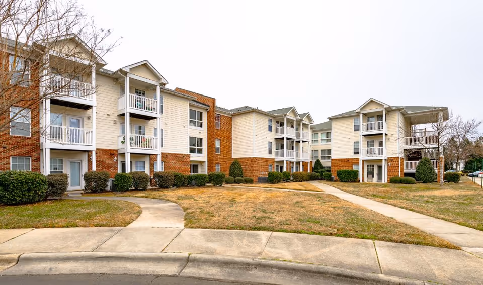 Exterior view of a multi-building senior living campus with balconies and lawns.