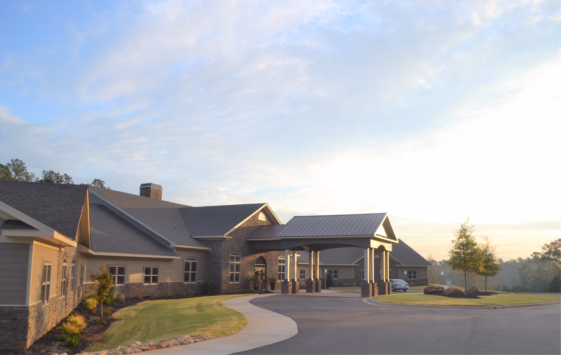 Exterior view of River Place senior living facility with curved driveway and covered entrance.