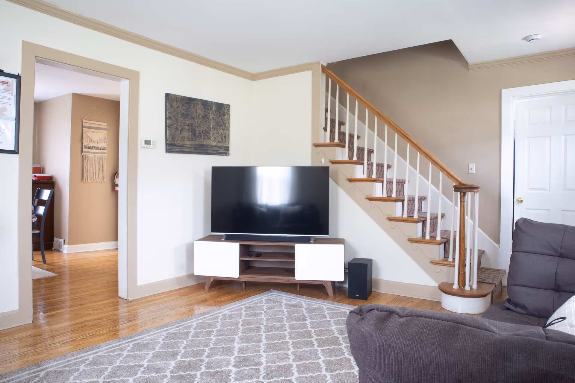 Cozy living room with a TV, staircase, couch, and patterned rug.