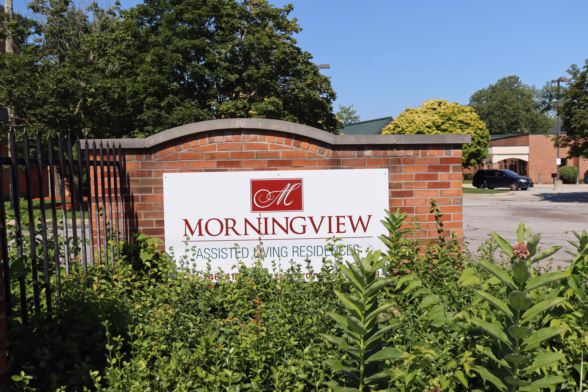 Brick wall sign reading Morningview Assisted Living Residences at entrance with surrounding greenery