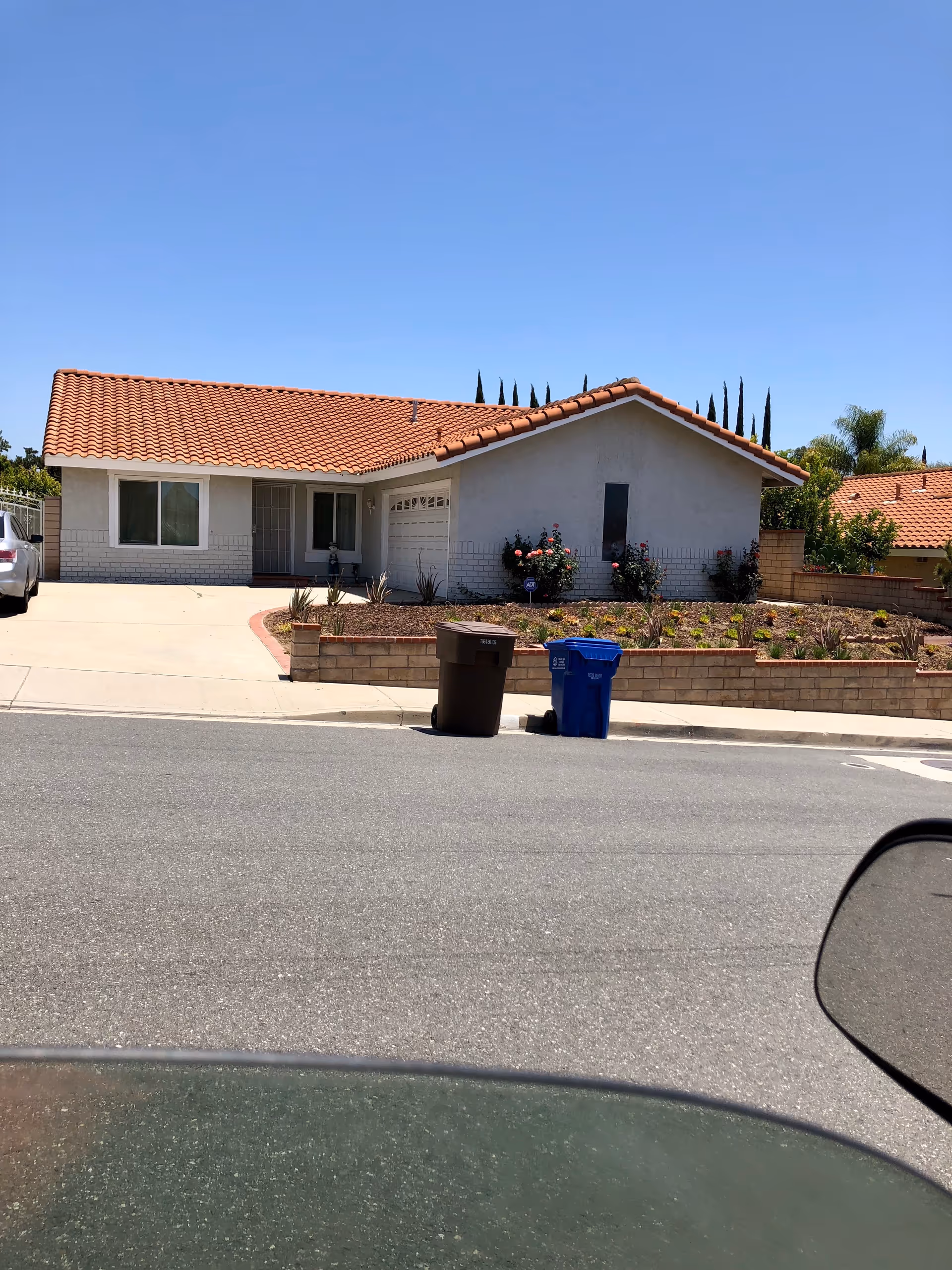 Front view of a single-story care facility with white exterior, red-tiled roof, and landscaped yard.
